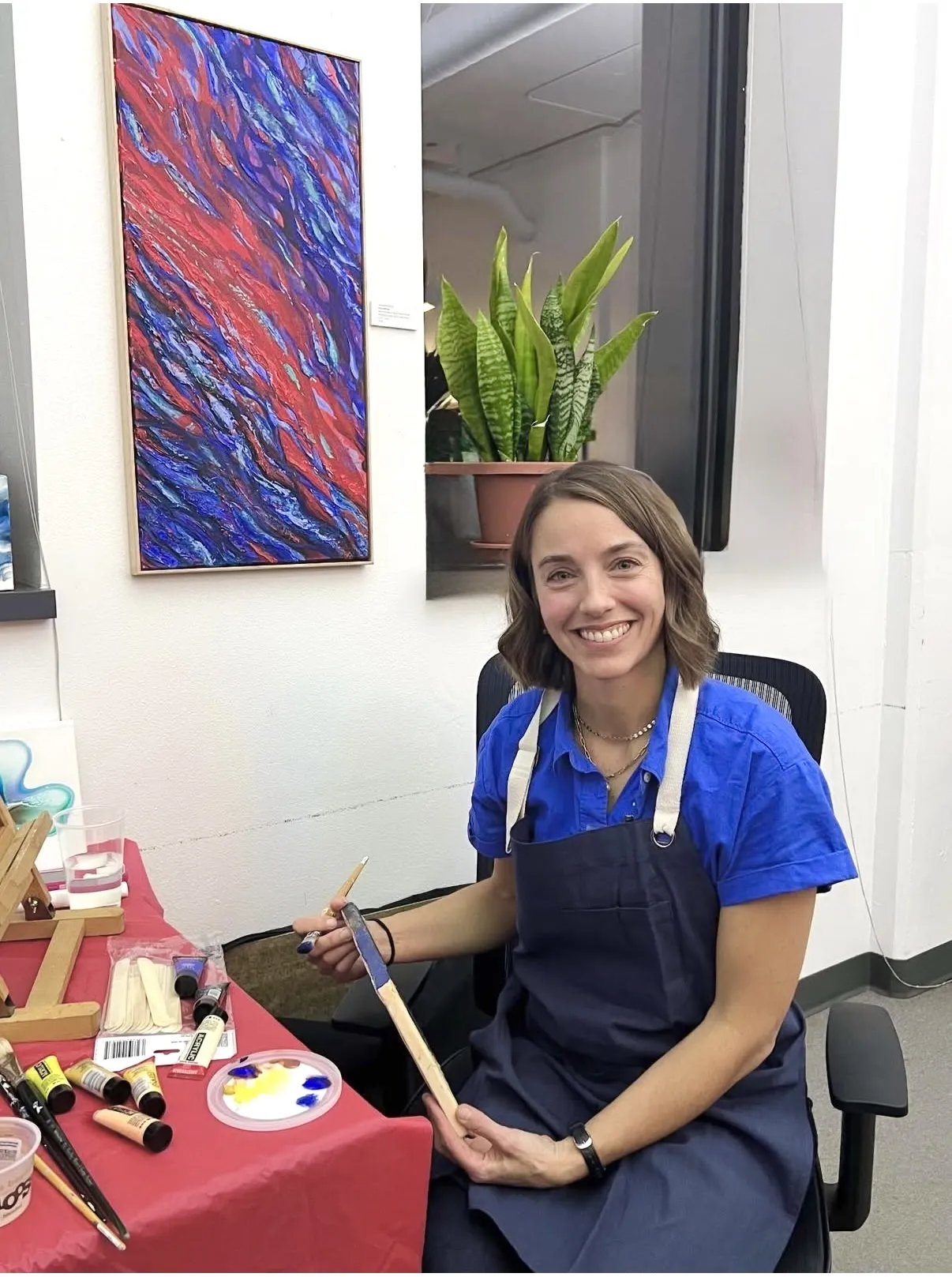 Jacqueline Biang seated at her painting table with Fire and Ice displayed behind her
